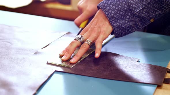 Mid-section of craftswoman cutting leather alt