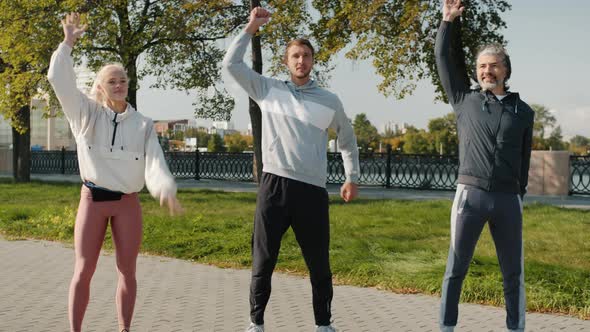 Fit People Young and Mature Doing Sports Exercises Outdoors on Summer Day alt
