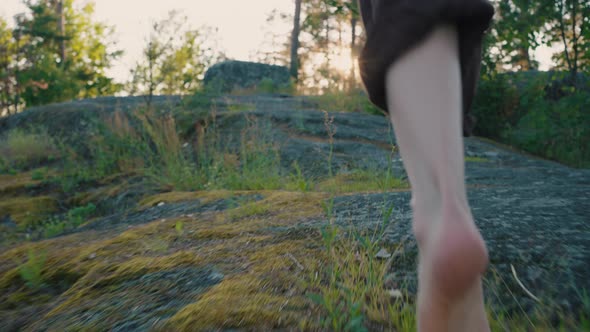 Barefoot Legs of Man Running on Rock Pathway Against Forest alt