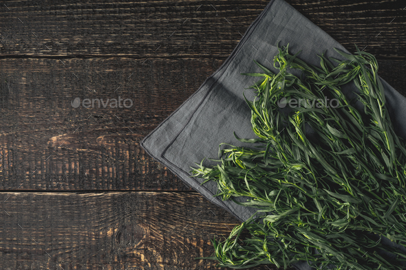 Tarragon on the grey napkin on the wooden table top view