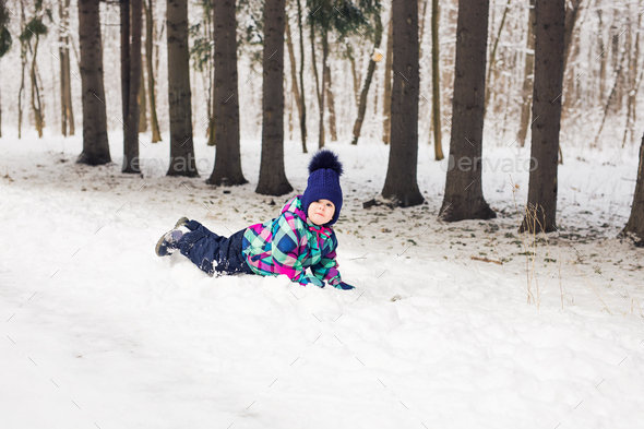 Laughing baby girl lying in the snow - Stock Photo - Images