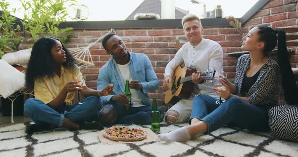 Friends which Meeting at Summer Party on Terrace and Singing Songs at Guitar, Drinking Beverages alt