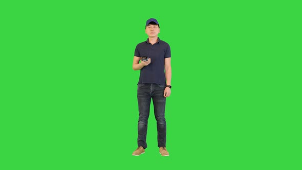 Young Man Gives Payment Terminal to Client After Work on a Green Screen Chroma Key