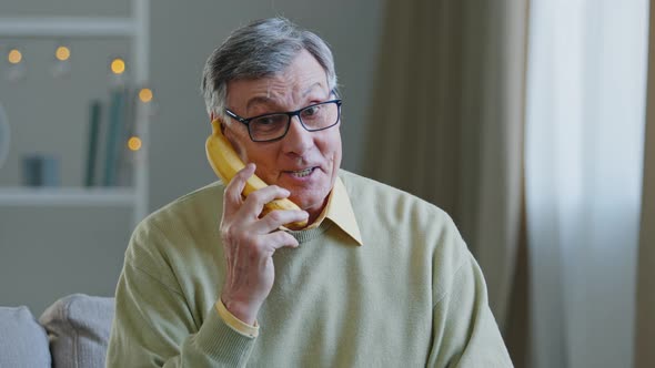 Portrait Funny Grandpa Retired Pretends to Speak Banana Like on Phone Humorous Conversation Old Man alt