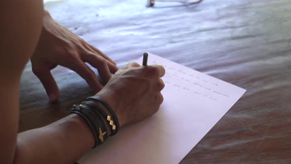 Male hands write love romantic letter on white paper to bride. Groom’s vow close up, wedding day