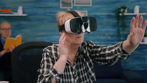 Retired Concentrated Senior Woman Using Virtual Reality Goggles in Living Room alt