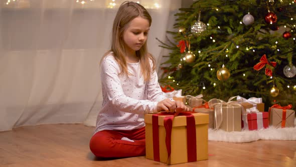 Happy Girl Opening Christmas Gift at Home alt