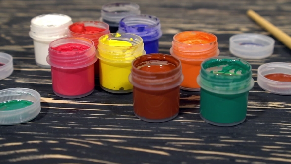 A Lot Of Varicolored Paint Gouache Jars With Brushes On Wooden Background