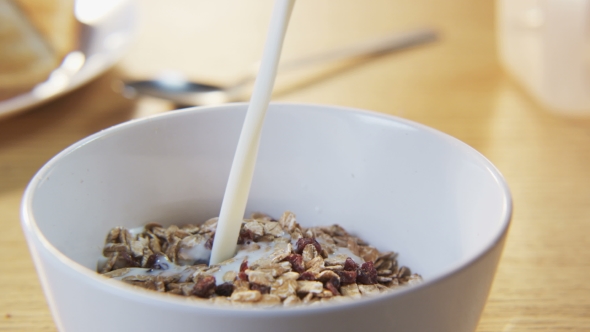 Pouring Milk Into a Bowl With Muesli alt