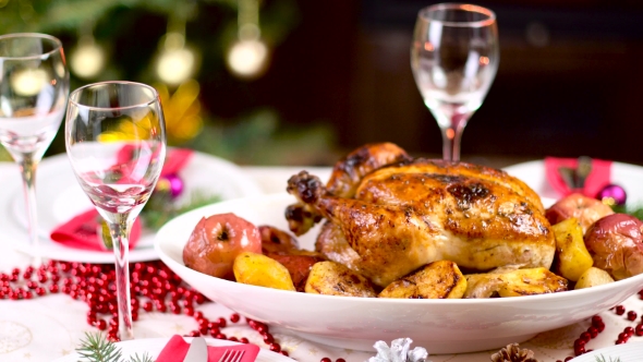 Roasted Chicken On Christmas Table In Front Of Fireplace And Tree With Lights