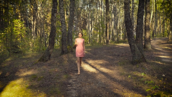 Young Girl In a Pink Dress Is Walking In The Woods