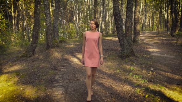 Young Girl In a Pink Dress Is Walking In The Woods