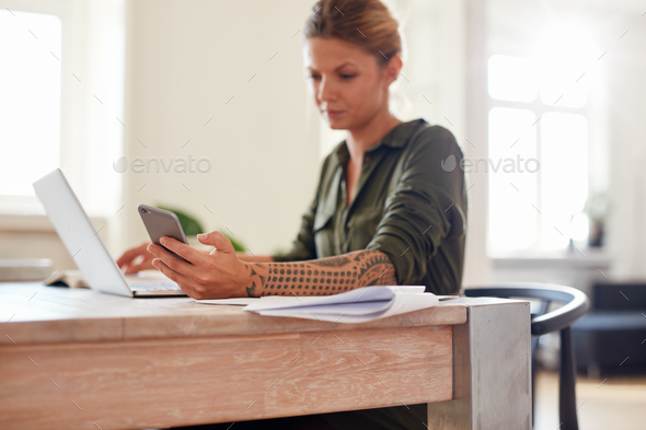 Woman at home office using mobile phone - Stock Photo - Images