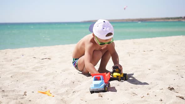 Happy Baby Playing with Cars on the Beach, on the Horizon Azure Sea and Blue Sky alt