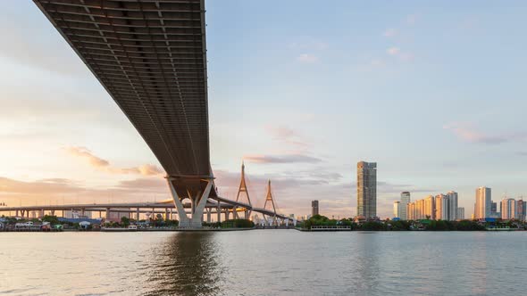 Large suspension bridge over Chao Phraya river at twilight, day to night, zoom out - time lapse