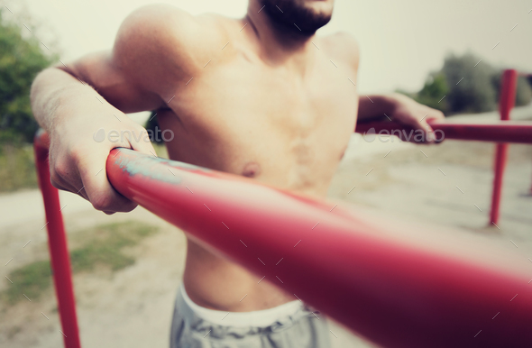 young man exercising on parallel bars outdoors - Stock Photo - Images