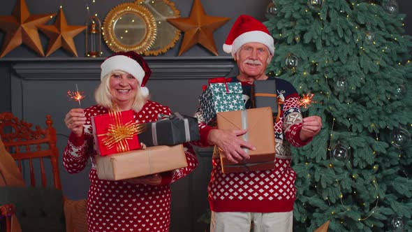 Smiling Married Senior Grandparents Man Woman Holding Christmas Gift Boxes and Bengali Sparkles alt
