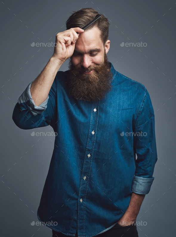 Cheerful man in beard combing his hair - Stock Photo - Images