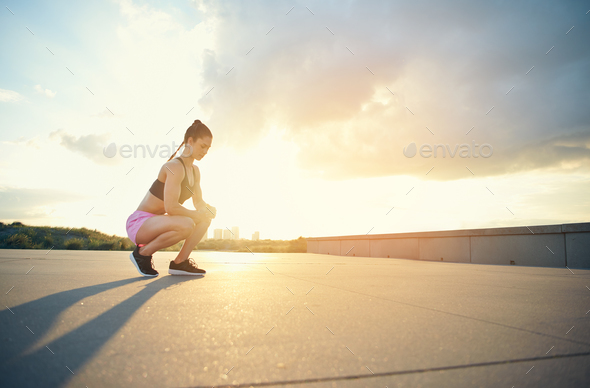 Female athlete squatting near ground outside - Stock Photo - Images