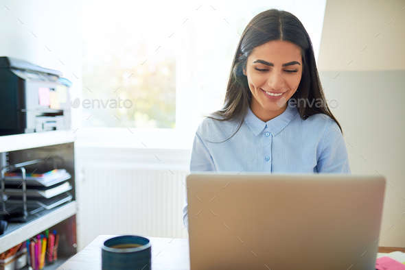 Laughing young Indian woman in front of laptop
