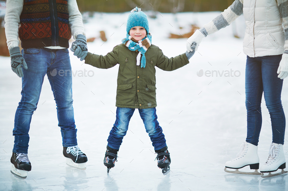 Smiling boy skating with parents - Stock Photo - Images