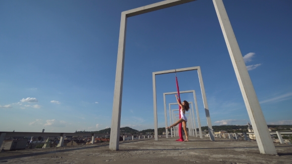 Beautiful Dancer On Aerial Silk. Young Sexy Woman Performs Acrobatic Stunts On The Rooftop Against alt