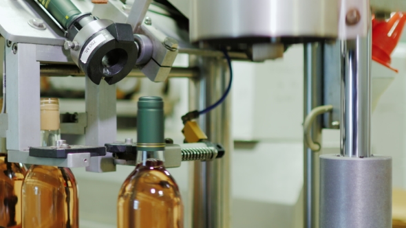 Industrial Conveyor Mechanism In The Winery. Close The Bottle With Pink Wine alt