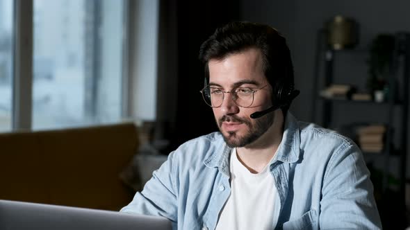 Smiling business man using laptop talking online call sits at desk. Happy confident male
