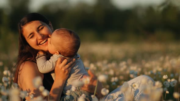 Slow Motion of a Young Happy Mother and Child in a Flower Field at Sunset