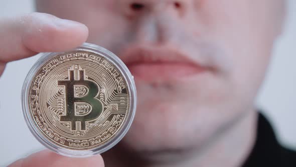 A Man Holds a Bitcoin in His Hand