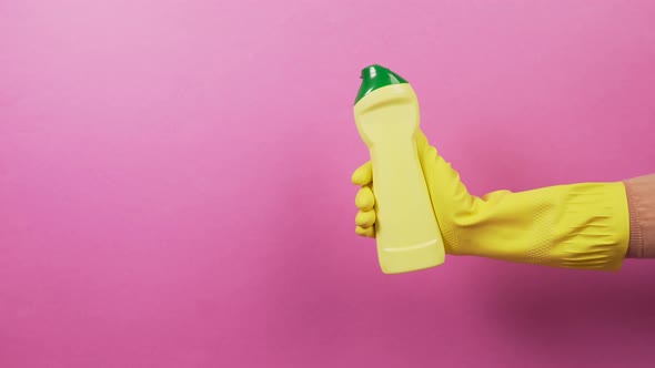 Hand in a Yellow Rubber Glove with a Plastic Bottle of Household Chemicals