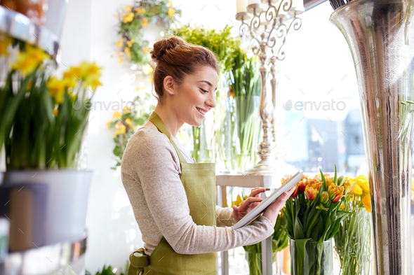 woman with tablet pc computer at flower shop - Stock Photo - Images