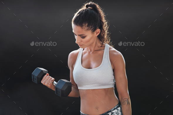 Strong and muscular female exercising with dumbbell