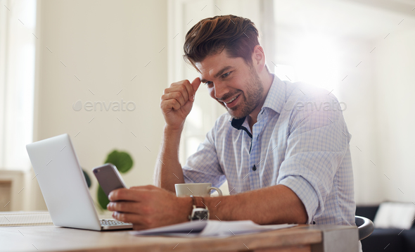 Happy young man at home office using mobile phone