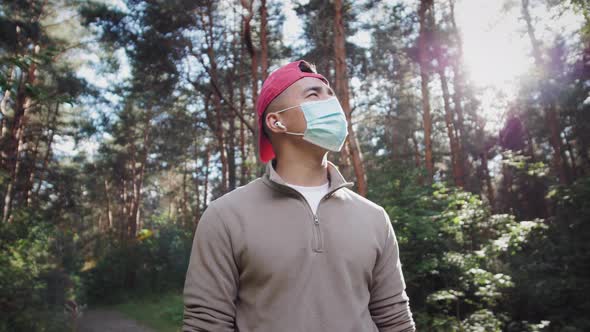 Young Asian Korean Tourist Man in Forest Wearing Medical Protective Mask Safe Travel Hiking in Park alt