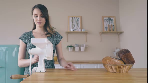Woman Installs Handle To Domestic Flour Mill on Wooden Table alt