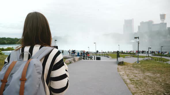 Camera Follows Thoughtful Local Woman Walking Towards Crowded Observation Deck at Mighty Niagara alt