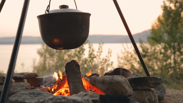 Brewed Fish Soup In An Old Pot. Cooking On Fire Near The Lake. Making Soup At Sunset