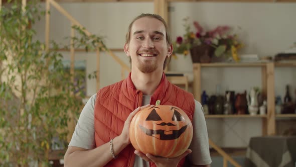 A Handsome Man is Holding a Pumpkin and Looking to the Camera alt