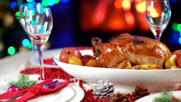 Roasted Chicken On Christmas Table In Front Of Fireplace And Tree With Lights