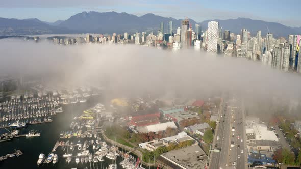 Epic aerial flying over the Vancouver waterfront on a foggy morning. alt