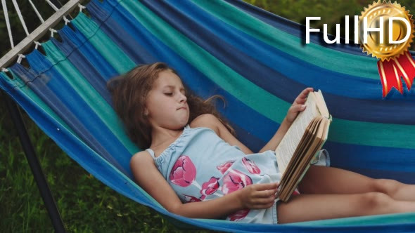 Young Curly Girl Reads a Book Lying in a Hammock