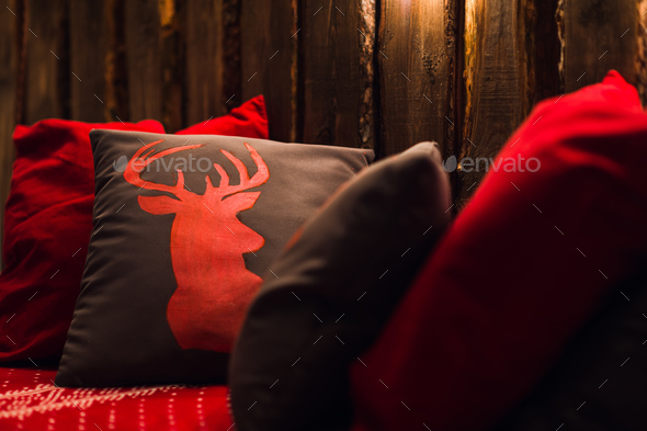 Deer head on red hand made pillow wooden background in interior