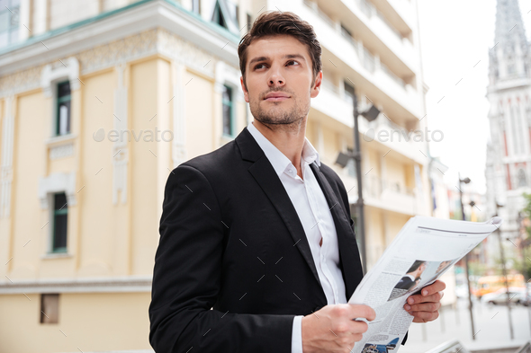 Businessman with newspaper standing on the street