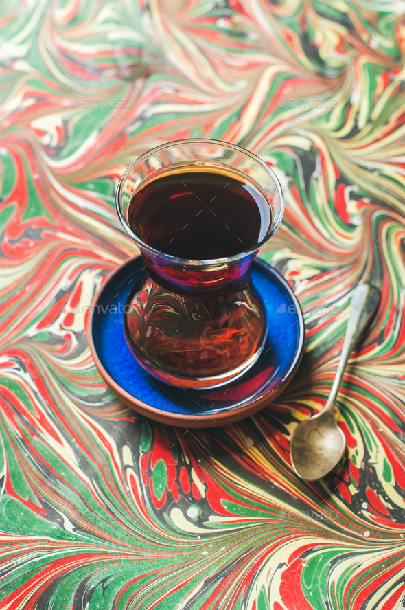 Turkish tea in traditional tulip glass and spoon, colorful background - Stock Photo - Images