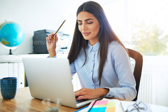 Thoughtful young Indian woman holding pencil - Stock Photo - Images