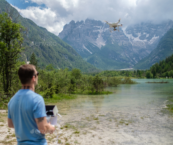 Man controls drone with mountains on background. Alps, Italy. - Stock Photo - Images