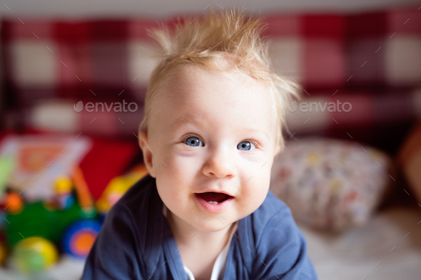 Little baby boy with spiky hair crawling on bed. Stock Photo by halfpoint