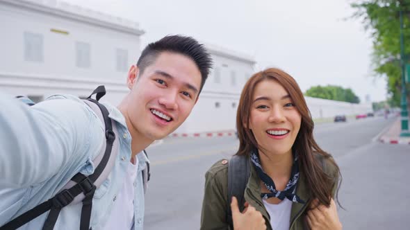 Asian couple backpacker use mobile phone selfie, take picture in city. alt