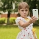 Little Girl in a White Dress Makes Selfi on the Meadow. - VideoHive Item for Sale